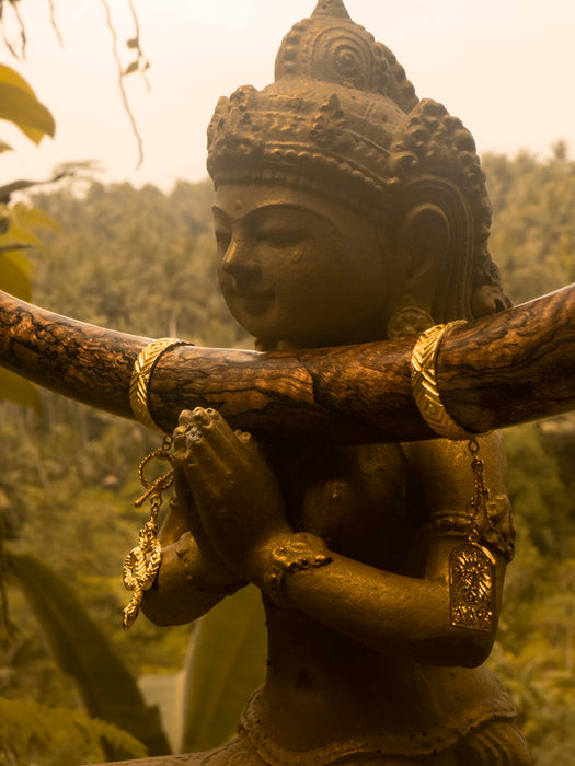 Statue of a deity holding a branch in a natural setting