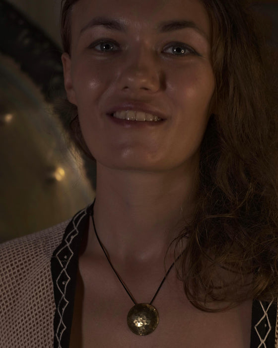 Woman wearing a necklace with a gold pendant in a dimly lit setting