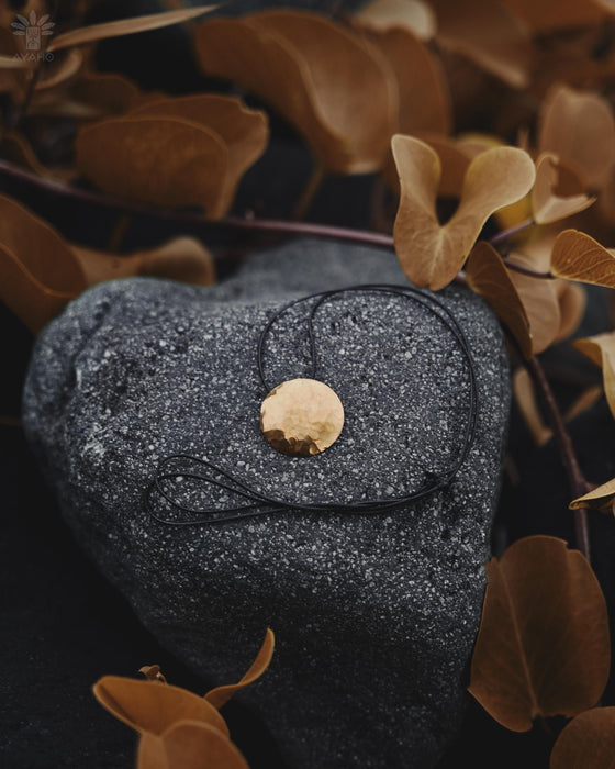 Black glittery pouch with a gold button on a dark background with brown leaves