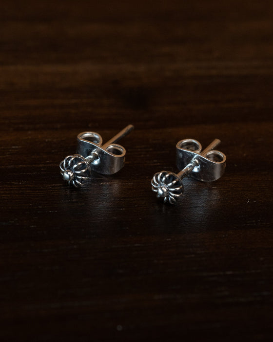 Close-up of hand-engraved floral stud earrings with cubic zirconia centers, displayed on a rustic wooden tray with dried lavender for boho charm.