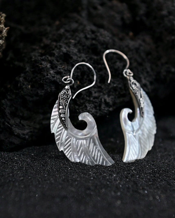 Exquisite Angel Wings earrings, crafted from lustrous mother-of-pearl and detailed sterling silver, radiating aesthetic grace and ethereal charm