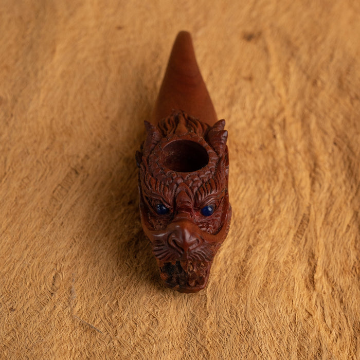 Decorative brown pipe with intricate carvings on a wooden surface