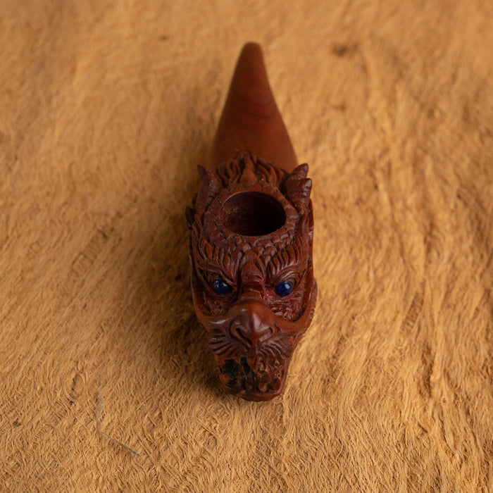 Decorative brown pipe with intricate carvings on a wooden surface
