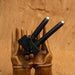 Black hair styling tools on a wooden hand sculpture against a wooden background