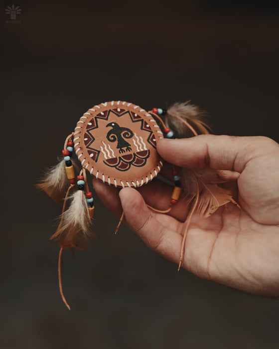 Handcrafted eagle feather brooch with painted details, symbolizing earth energy and spiritual transition, pinned to a tribal-printed shawl