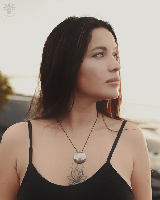Woman wearing a black tank top with a necklace, standing outdoors.