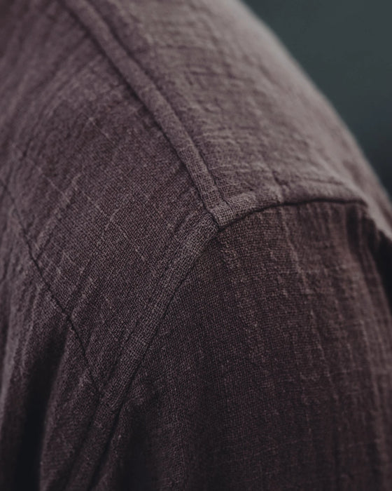 Close-up of a textured brown fabric with a brand logo in the corner.
