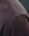 Close-up of a textured brown fabric with a brand logo in the corner.
