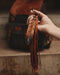 Tiny preserved owl feather in a glass vial pendant, attached to a braided leather necklace for everyday spiritual protection.
