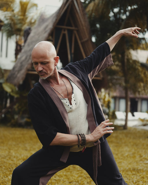 Man in traditional martial arts attire practicing in a natural setting