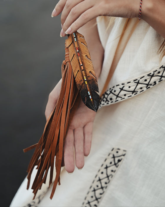 Tiny preserved owl feather in a glass vial pendant, attached to a braided leather necklace for everyday spiritual protection.
