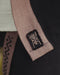 Close-up of a brown belt with a logo on a black garment, featuring the AYAGO brand.