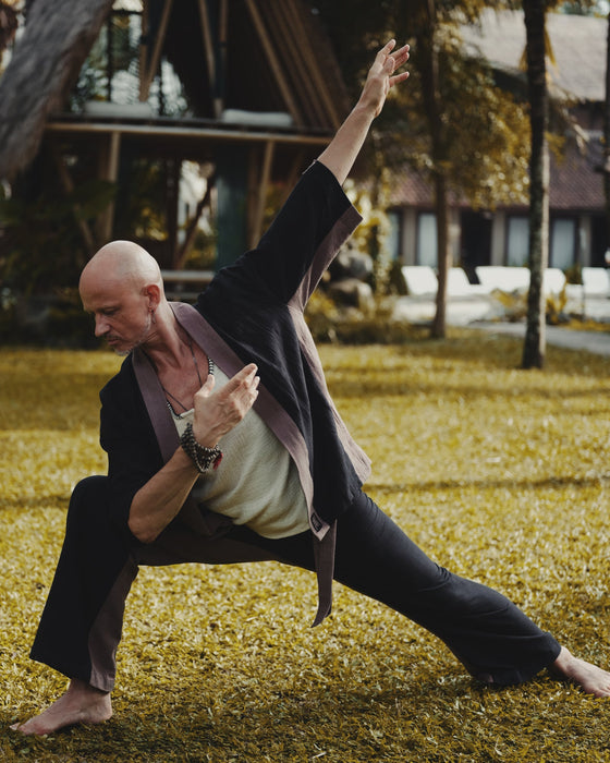 Man in a suit performing a martial arts move outdoors on grass