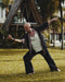Man practicing martial arts on grass with a traditional building in the background