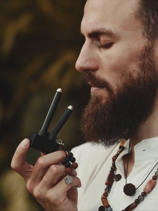Man with a beard holding a walkie-talkie with a blurred natural background