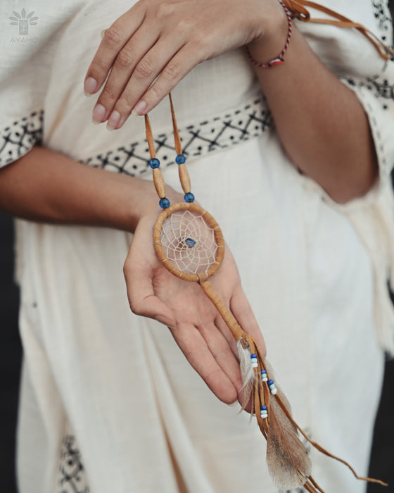 Close-up of a traditional-style dream catcher amulet with amethyst and howlite beadsx, hanging from a car mirror.