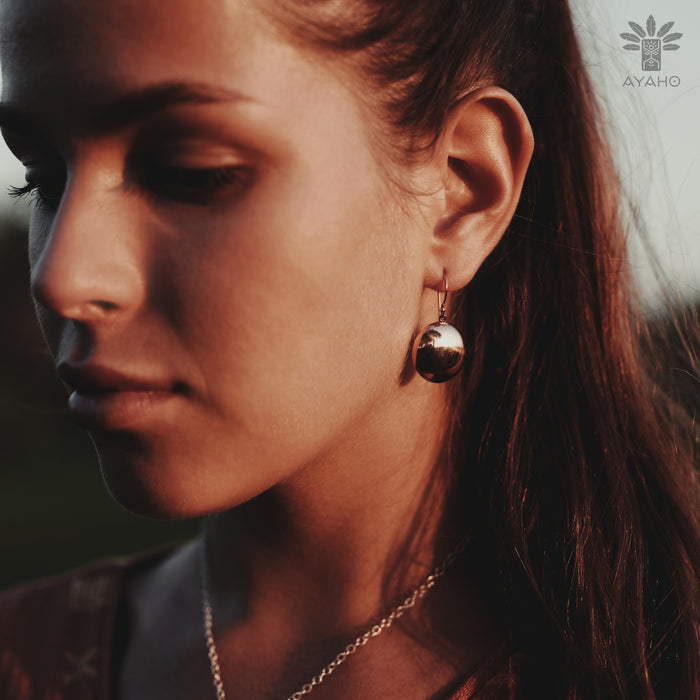 Close-up of a woman wearing gold earrings with a blurred background