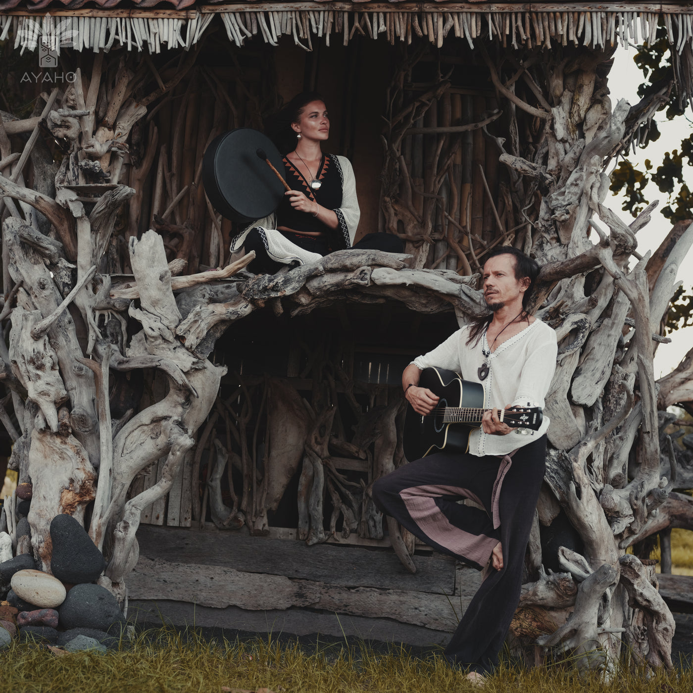 Two people in a rustic setting with wooden structures and natural elements.