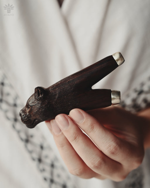 Hand holding a small wooden animal figurine against a blurred background