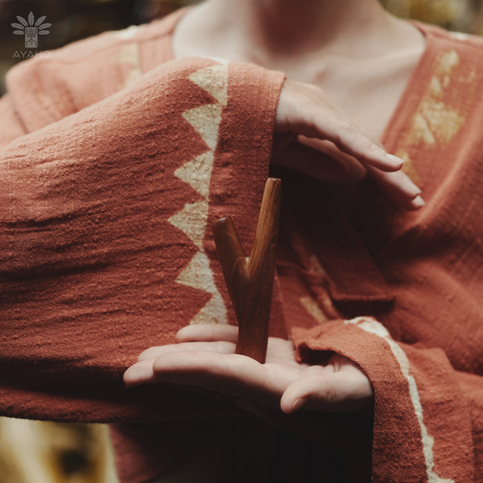 Person wearing a textured red garment holding a wooden object with a blurred background