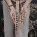 Person holding a belt with decorative patterns against a blurred natural background