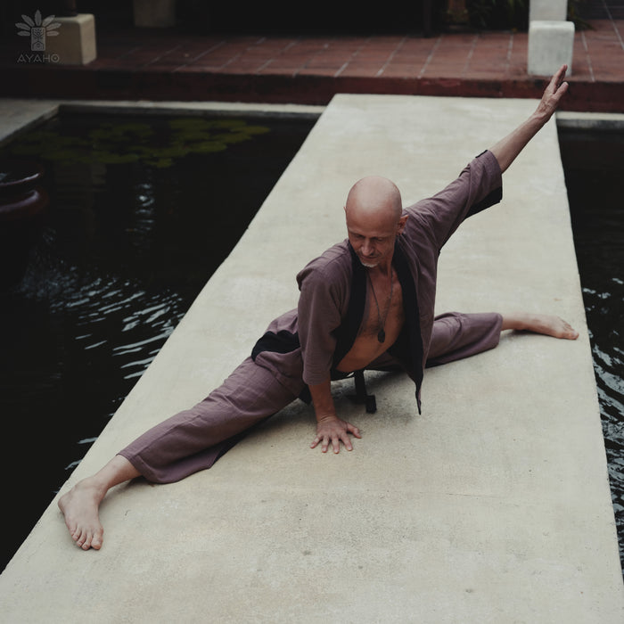 Man in a yoga pose on a stone platform by a pool