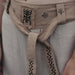 Close-up of a beige belt with black patterns on a person wearing a light gray shirt.