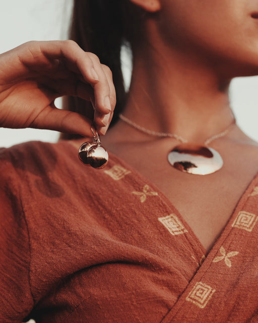 Person wearing a gold pendant necklace with a blurred background