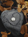 Heart-shaped stone with a necklace on a dark background with brown leaves