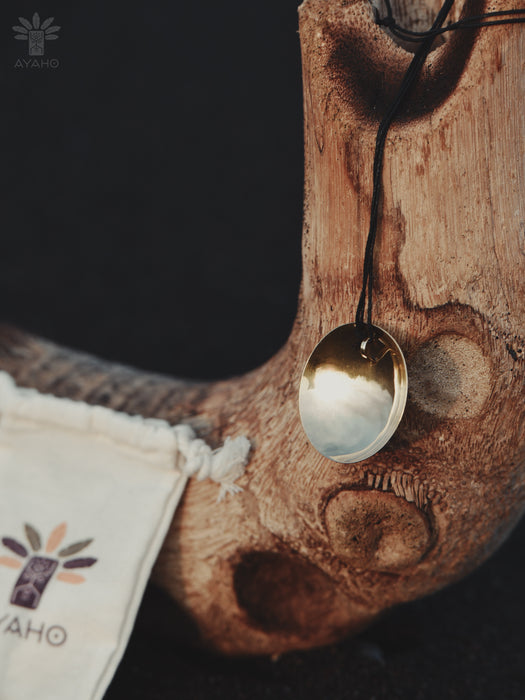 Gold pendant on a wooden surface with a branded bag in the background