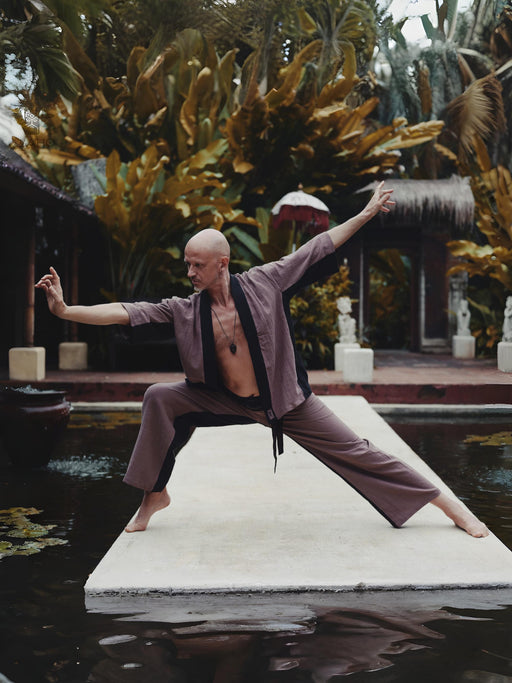 Person in martial arts pose on a platform with lush greenery in the background