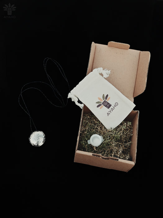 Product packaging with a necklace, pouch, and branded card on a black background