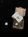 Product packaging with a necklace, pouch, and branded card on a black background