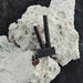 Black and silver tool with decorative elements on a textured rock surface