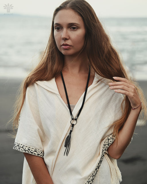 Handmade feather charm with turquoise beads and leather cord, resting on a bed of sage and dried flowers for a natural boho vibe.