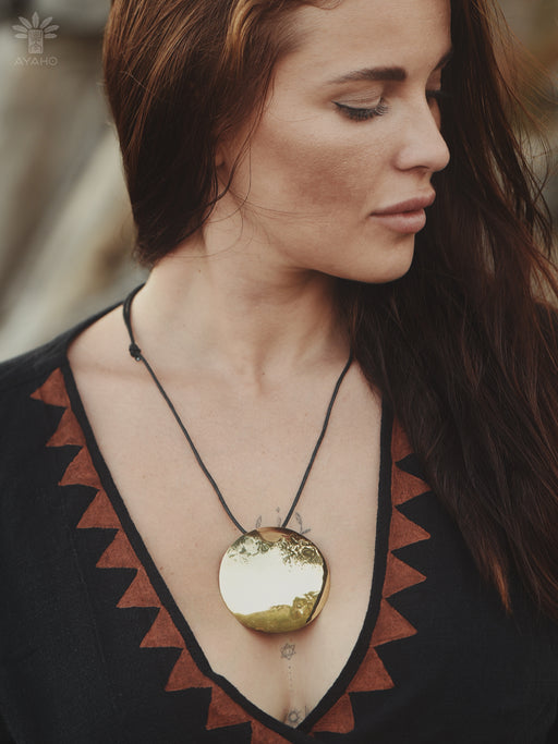 Woman wearing a necklace with a large round pendant, blurred background