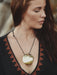 Woman wearing a necklace with a large round pendant, blurred background