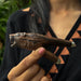 Person holding a wooden pipe with a natural finish outdoors