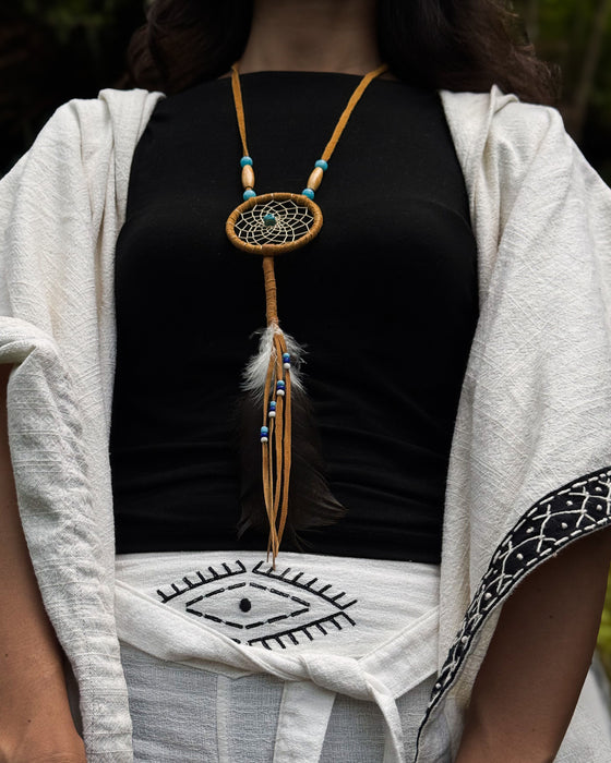 Close-up of a traditional-style dream catcher amulet with amethyst and howlite beadsx, hanging from a car mirror.