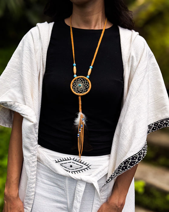 Close-up of a traditional-style dream catcher amulet with amethyst and howlite beadsx, hanging from a car mirror.