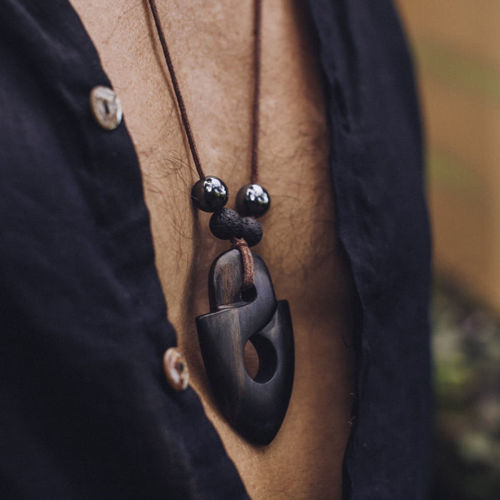 Man wearing a sacred ebony wood amulet, strung with hematite and volcanic lava beads, crafted as a talisman for strength and protection
