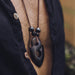 Man wearing a sacred ebony wood amulet, strung with hematite and volcanic lava beads, crafted as a talisman for strength and protection