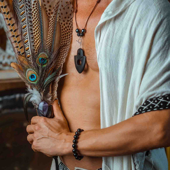 Man wearing a sacred ebony wood amulet, strung with hematite and volcanic lava beads, crafted as a talisman for strength and protection