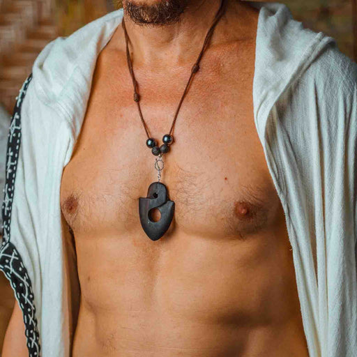 Man wearing a sacred ebony wood amulet, strung with hematite and volcanic lava beads, crafted as a talisman for strength and protection