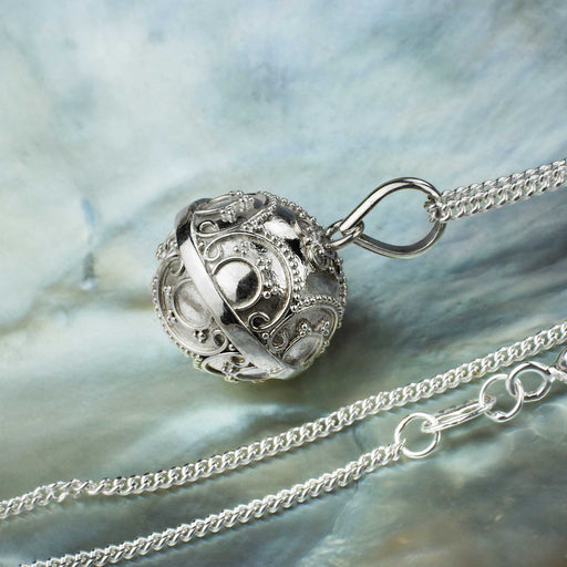 Detailed view of a handcrafted silver harmony bell pendant, serving as a talisman amulet, associated with heart healing and negative energy protection