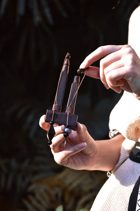Close-up of hands holding a small wooden tool against a dark background