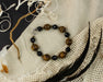 Bracelet with brown and black beads on a textured fabric background