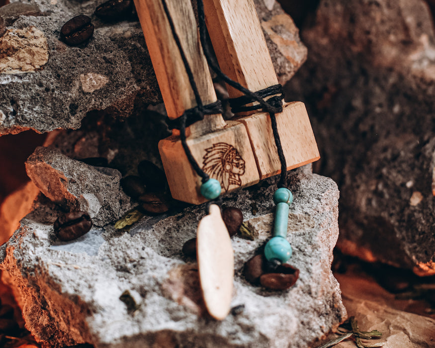 Close-up of artisan-crafted ceremonial pipe showing rich wood grain and spiritual carvings against tropical leaves