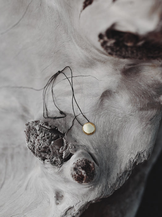 Model wearing a copper shaman mirror necklace, reflecting light onto a flowy linen dress for earthy elegance.