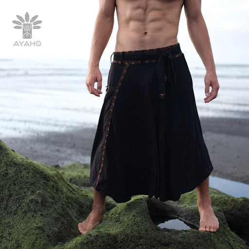 Model poses on ancient steps in boho-style unisex harem pants, featuring organic cotton and sacred geometry details, merging Aladdin flair with yoga functionality.